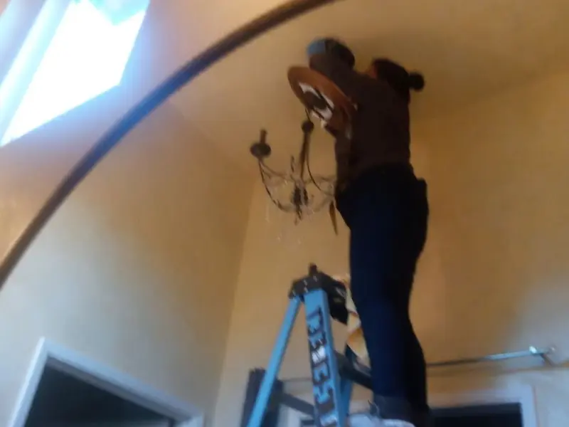 Electrician installing a chandelier in a Blendon residence